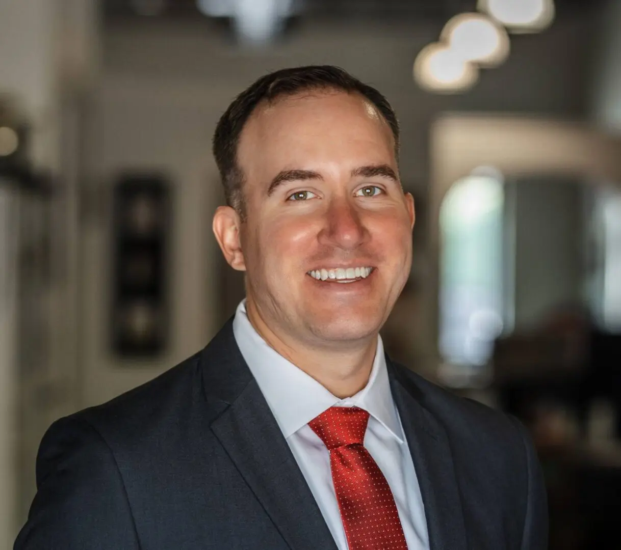 A man in a suit and tie smiling for the camera.