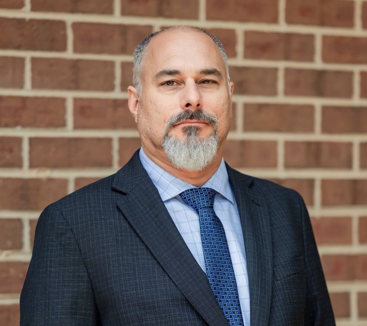 A man in a suit and tie standing next to a brick wall.