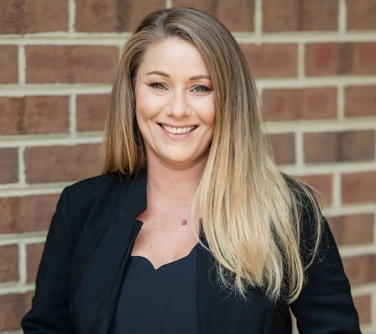 A woman standing in front of a brick wall.